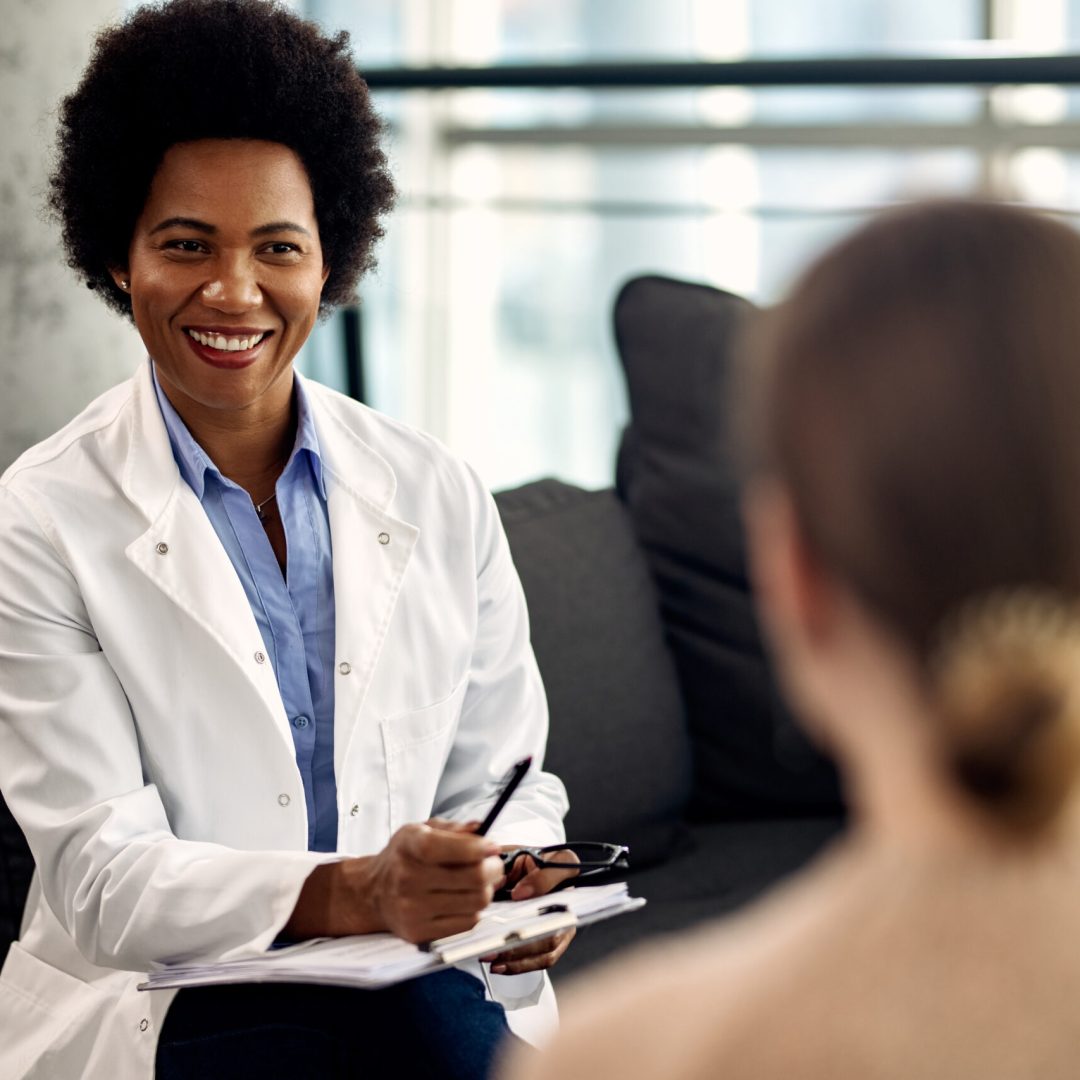 Happy black counselor communicating with a patient during a psychotherapy appointment at her office.